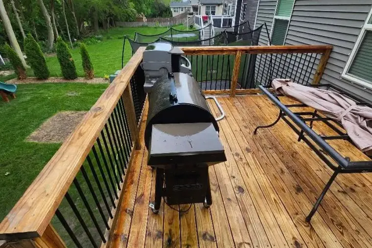 Clean wooden deck boards with a railing and green yard behind